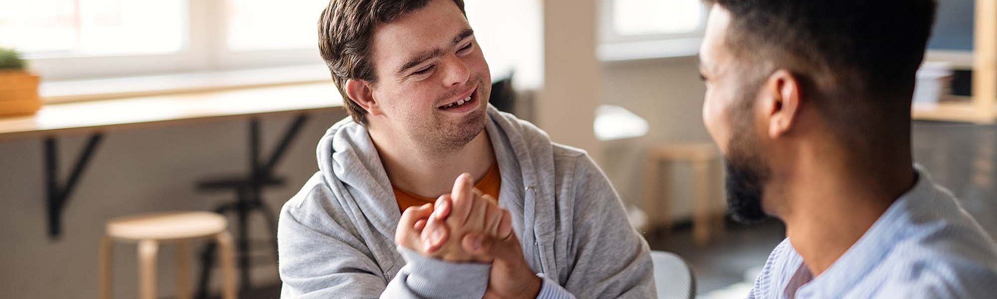 Zwei Männer, einer davon mit Down Syndrom, machen einen Bro-Handshake